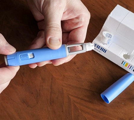 Close-up of a person handling a Mounjaro injection pen with packaging visible