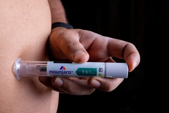 Close-up of a person administering Mounjaro injection in their abdomen.